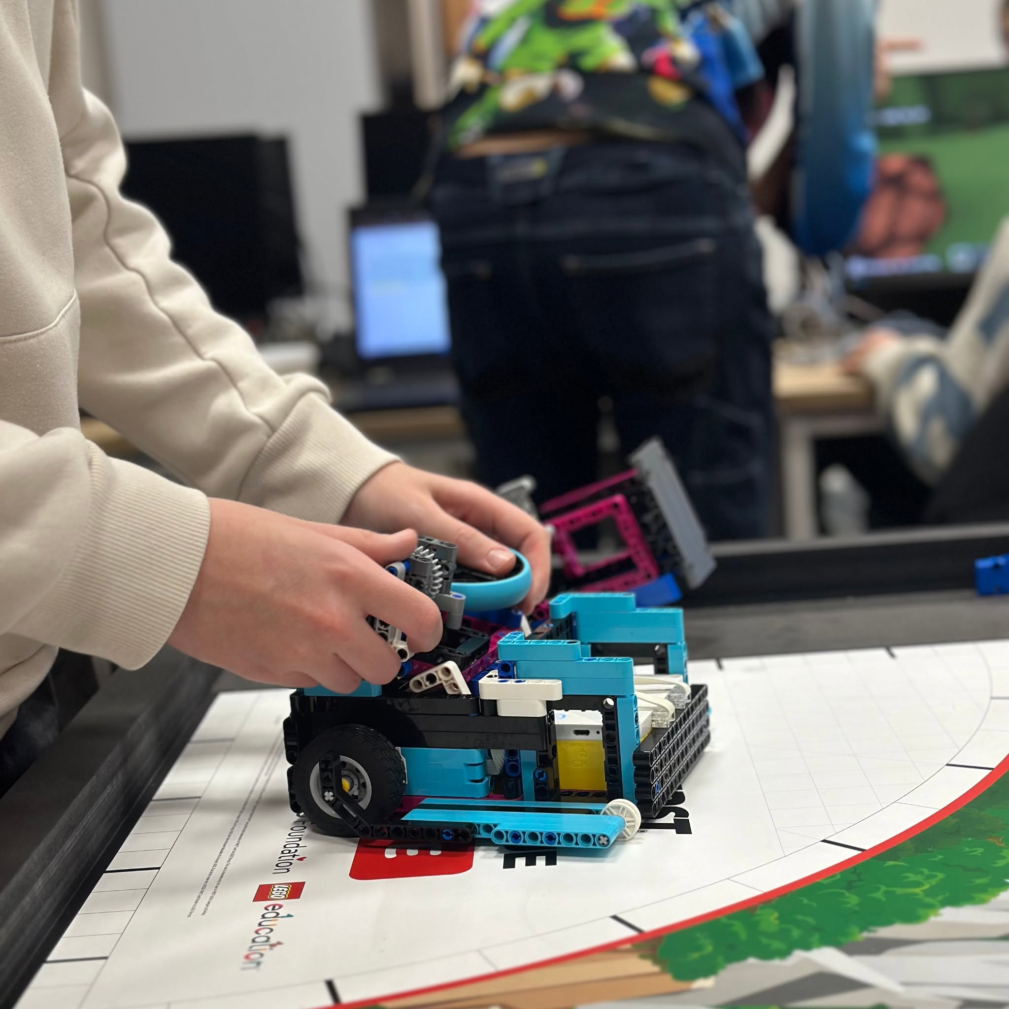 Jeune assemblant un robot Lego Spike sur un tapis de mission