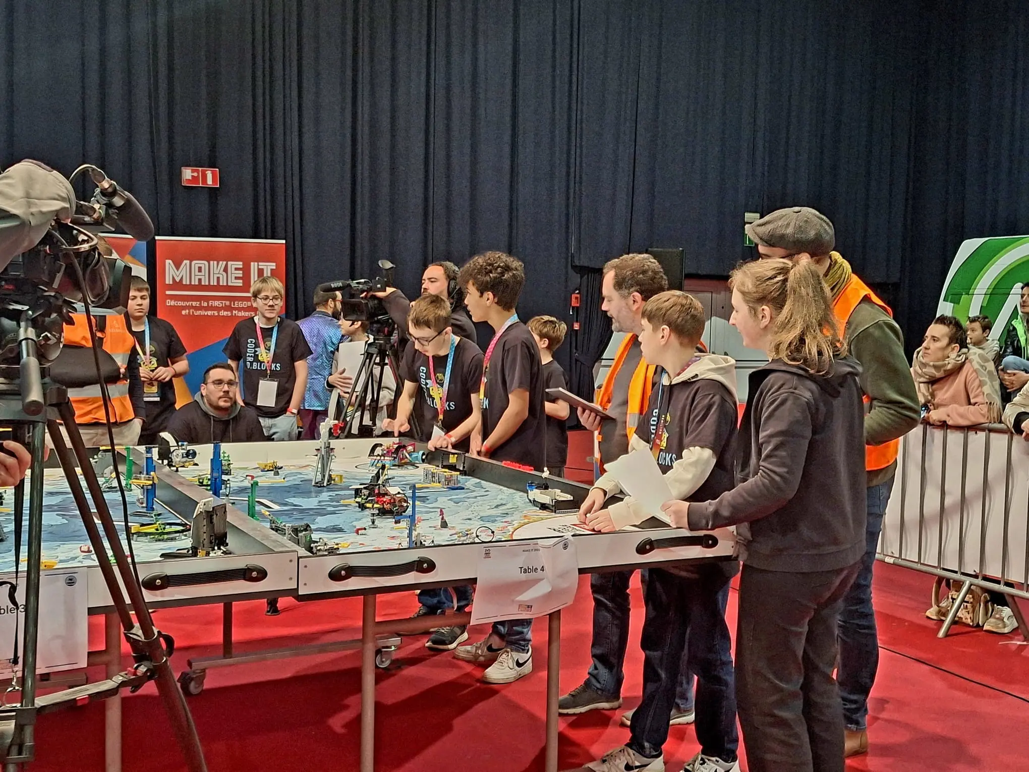 Équipes rassemblées autour d'une table de compétition FIRST Lego League