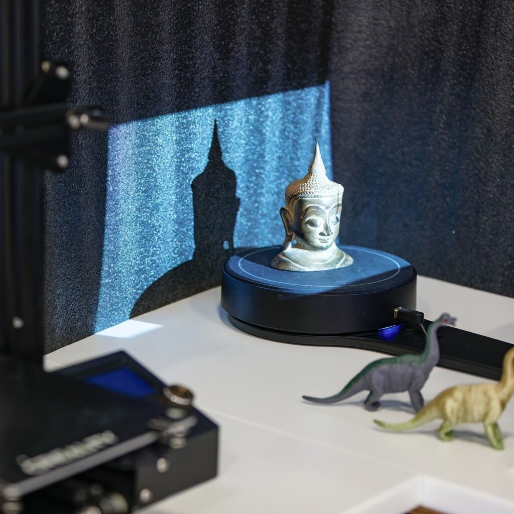 Un scanner 3D relève une petite sculpture posée sur son plateau tournant.