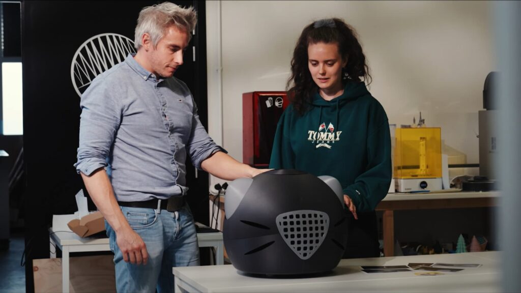 Deux personnes examinent un prototype imprimé en 3D posé sur une table du FabLab.